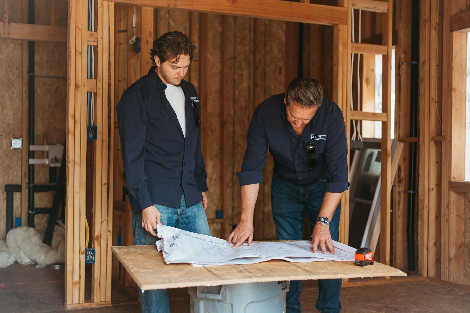 Paul and Simon reviewing blueprints inside a framed home