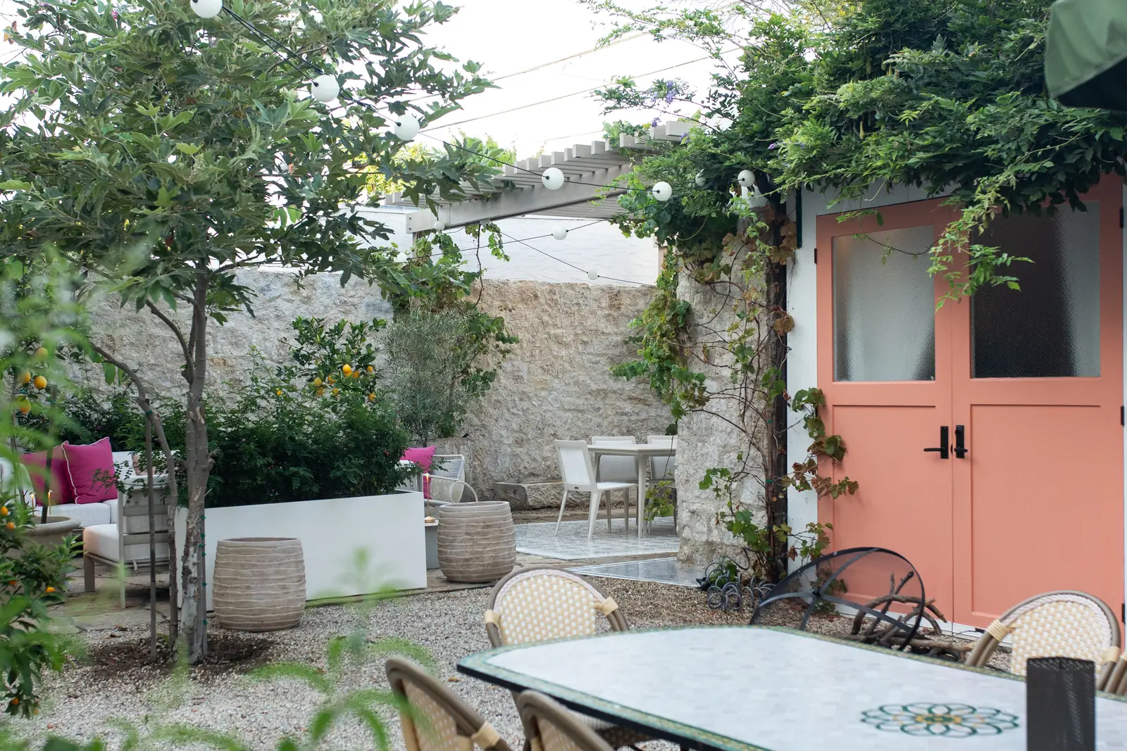 Landscaped courtyard with pergola, string lights, and gravel dining patio