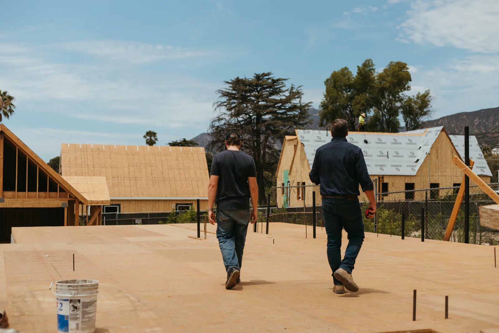 Walking the subfloor deck of a new build with framed homes going up behind