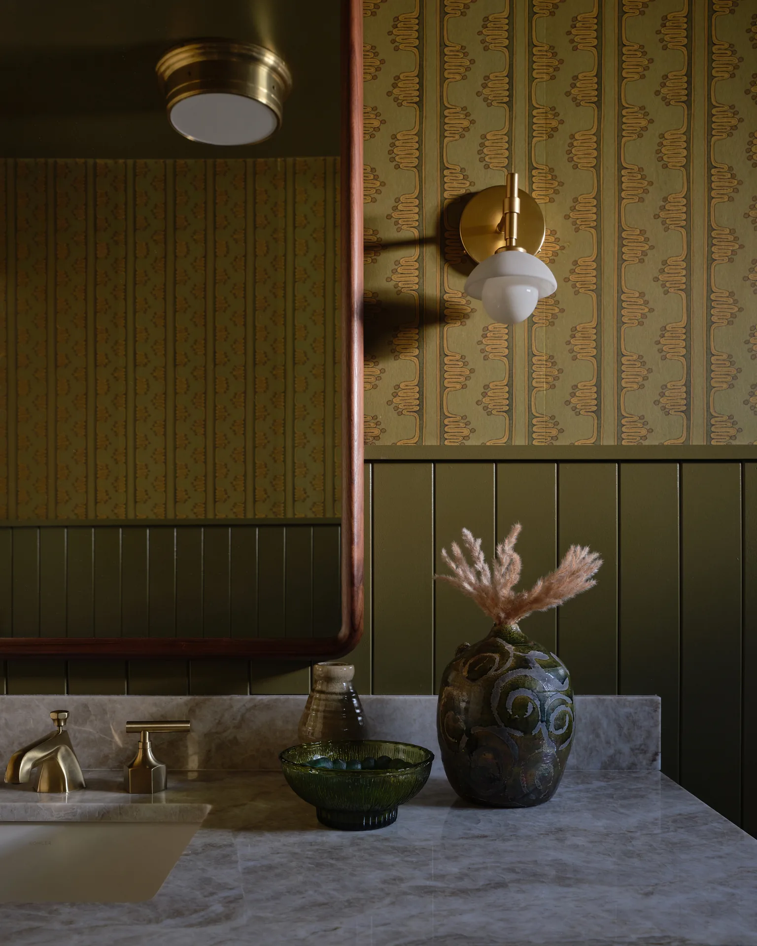Powder room with patterned wallpaper, olive beadboard, and marble vanity top