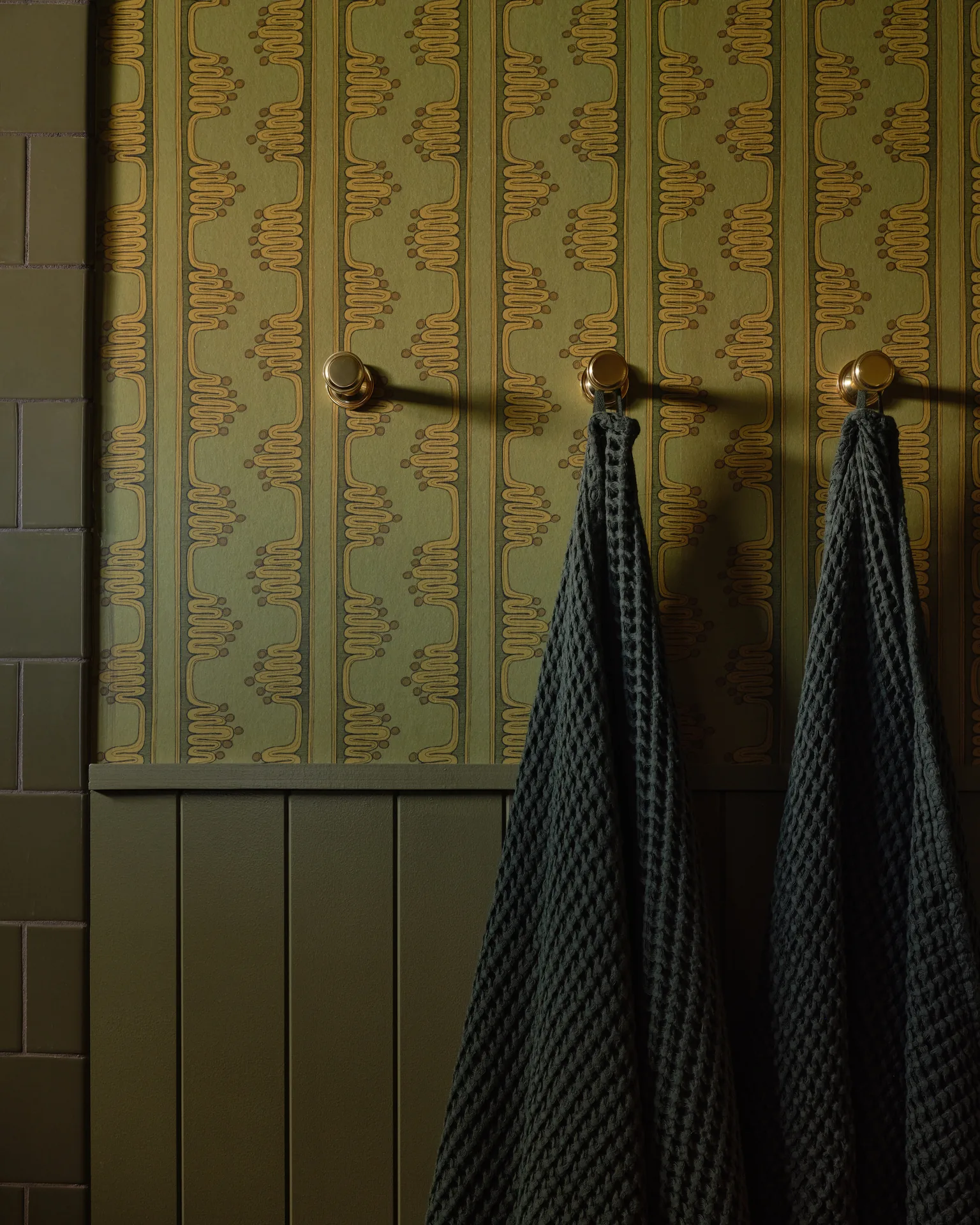 Powder room towel hooks on olive beadboard and patterned wallpaper