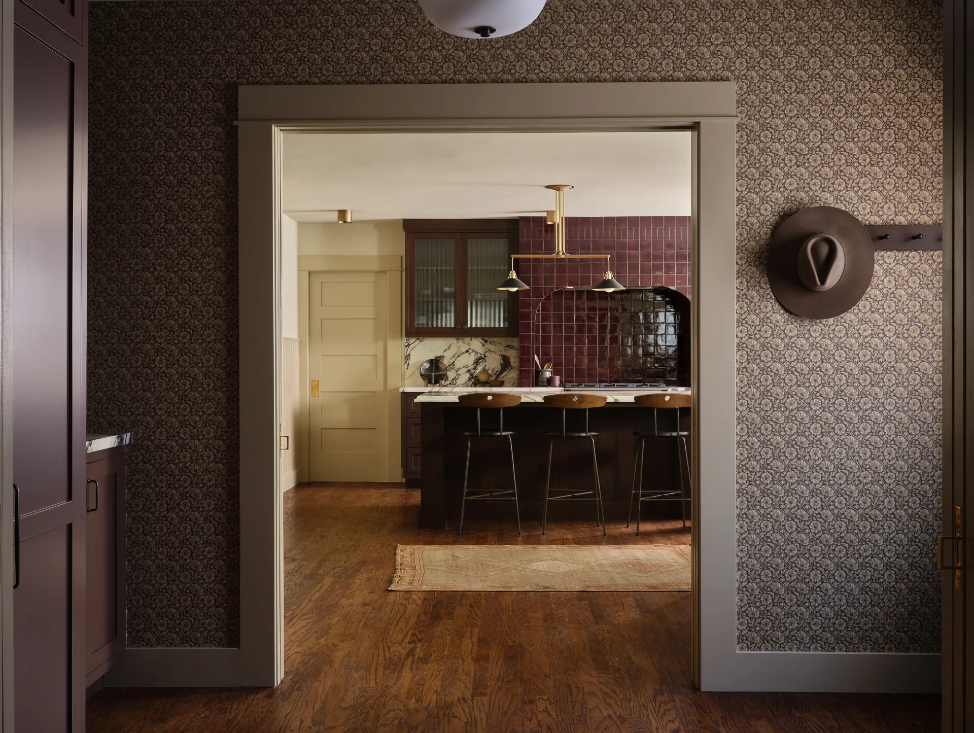 View from the wallpapered hall into the remodeled Craftsman kitchen