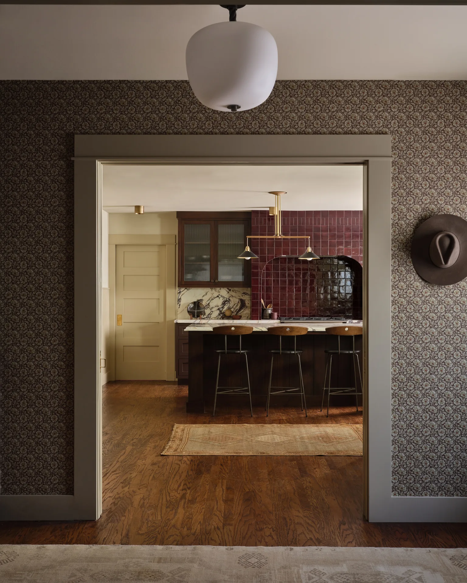 Doorway framing the kitchen island and burgundy tile alcove