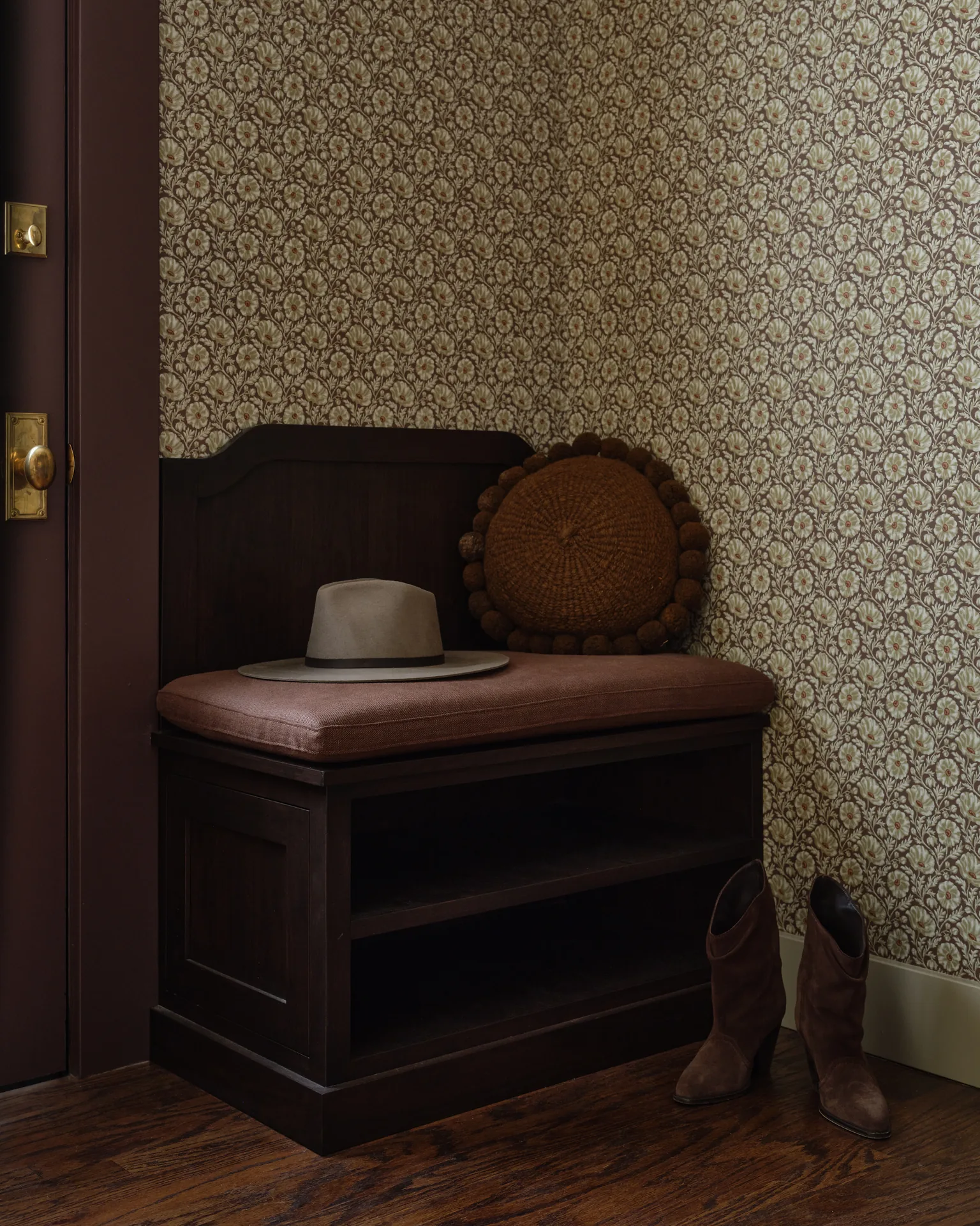 Mudroom bench in stained wood with patterned wallpaper